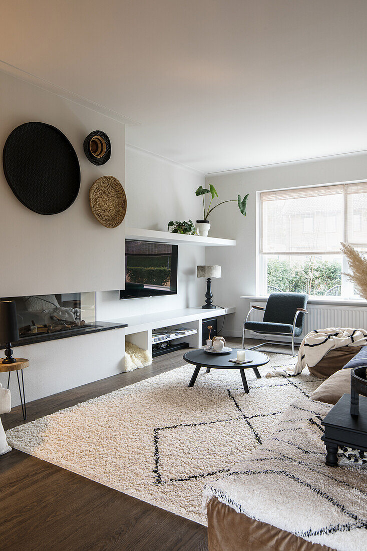 Living room with modern fireplace, fluffy rug and wall decoration made from baskets