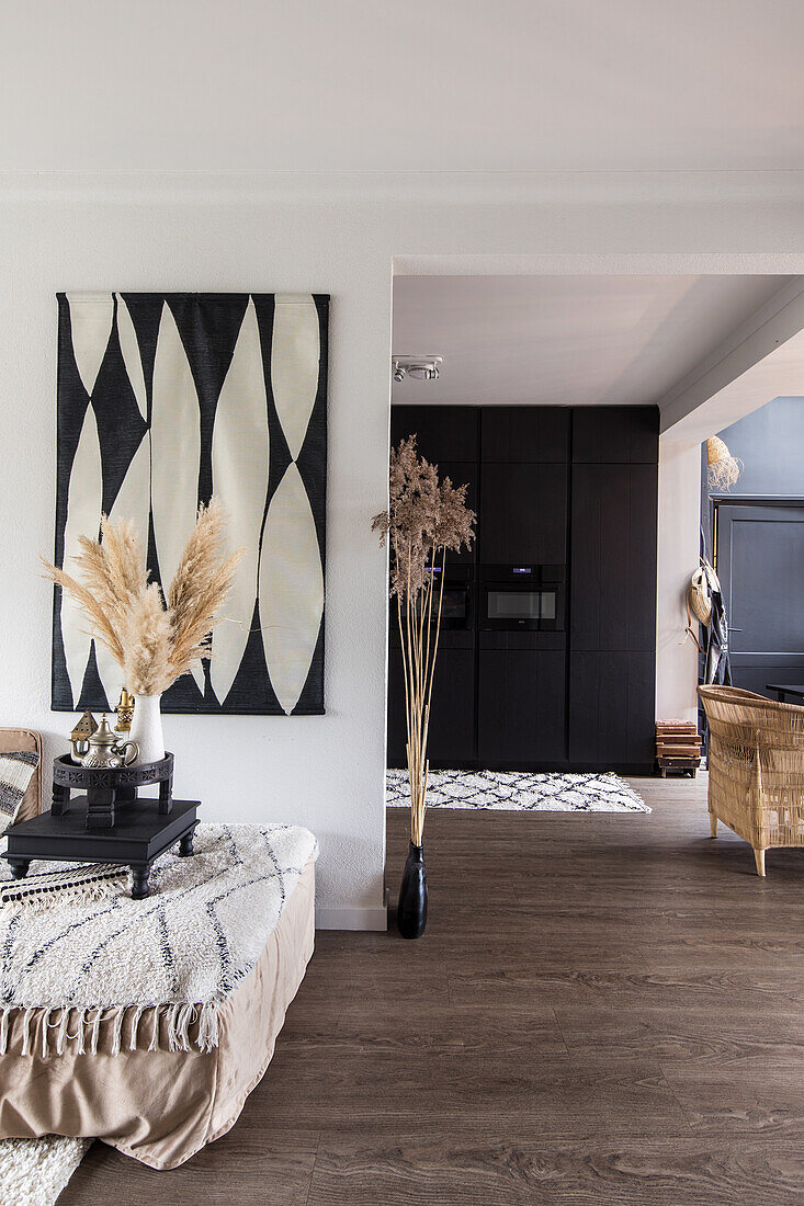 Modern living room corner with abstract mural, floor vase and dried grasses