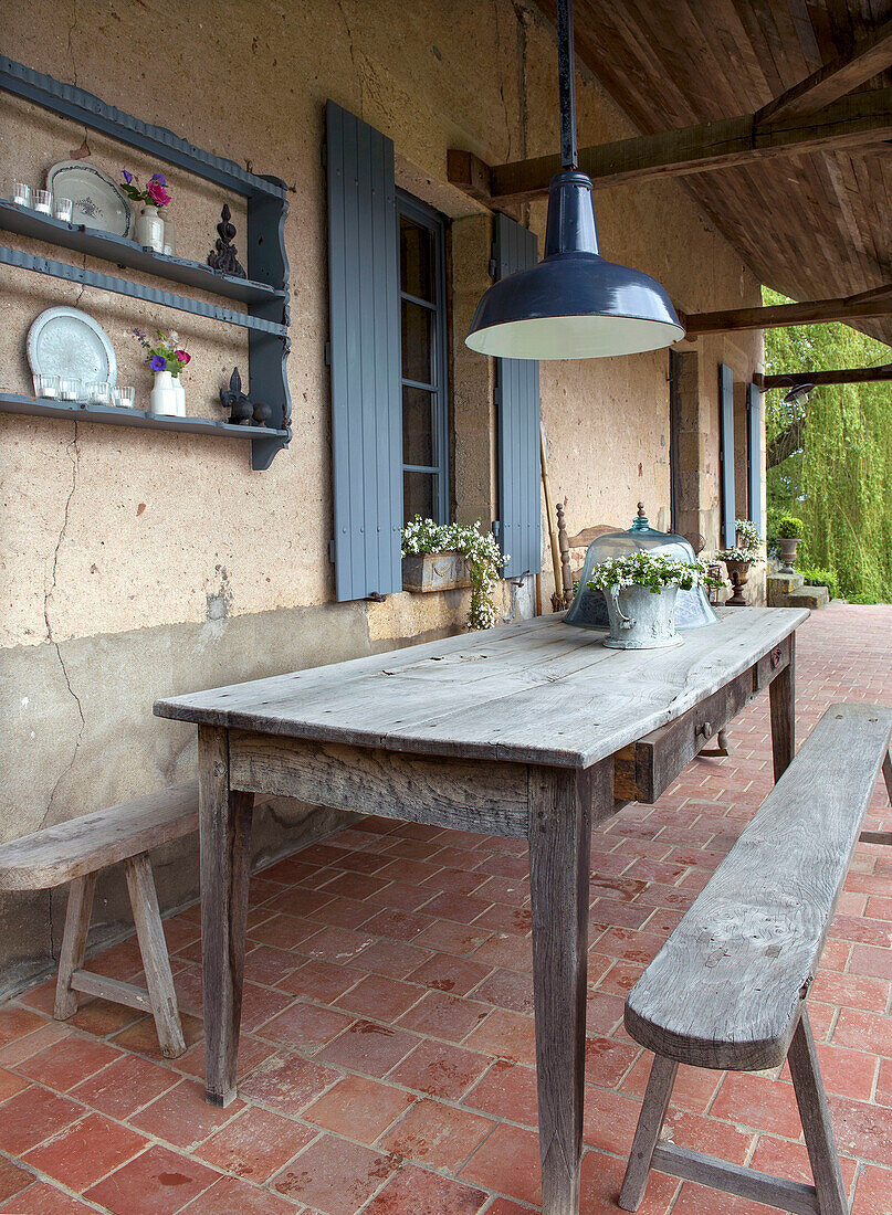 Covered, rustic veranda with table and wooden benches