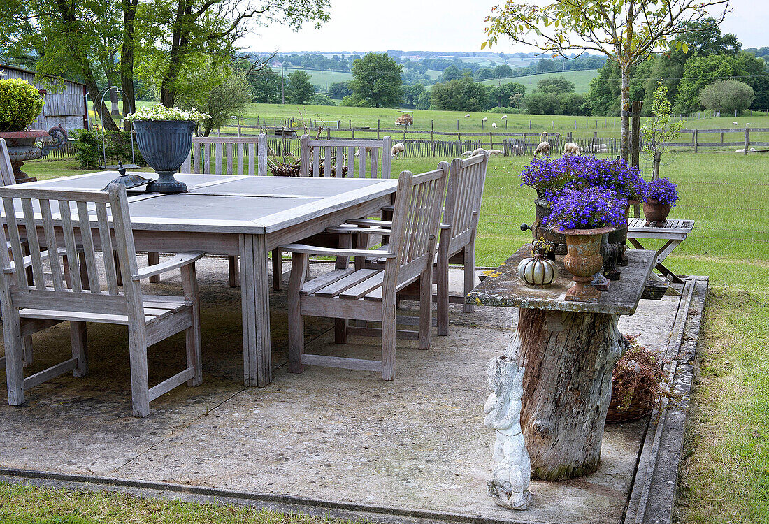 Wooden patio seating area with flower arrangements and countryside views