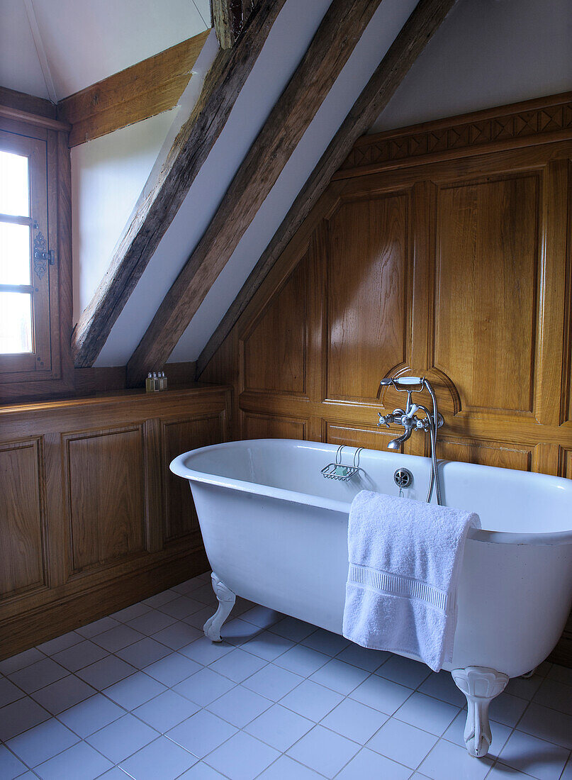 Vintage freestanding bathtub in the bathroom with dark wood panelling
