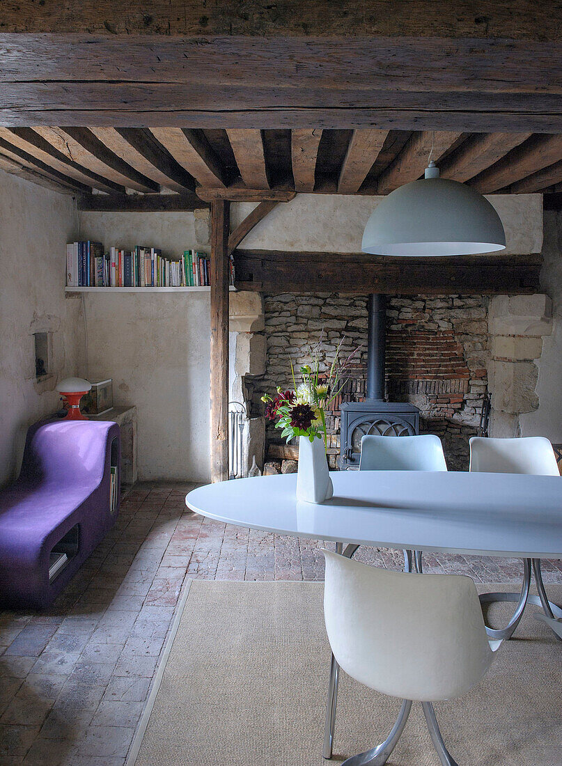 Cosy dining area with designer furniture and wood-burning stove in front of a brick wall