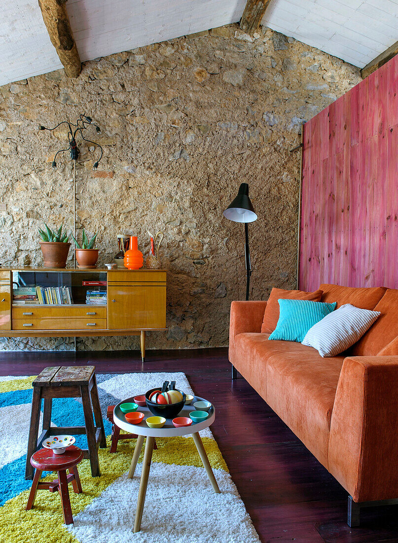 Wohnzimmer mit Retro-Charme, Steinwand und farbenfrohen Akzenten