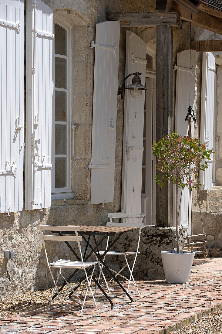Klapptisch und -stühle vor traditionellem Steinhaus mit Fensterläden