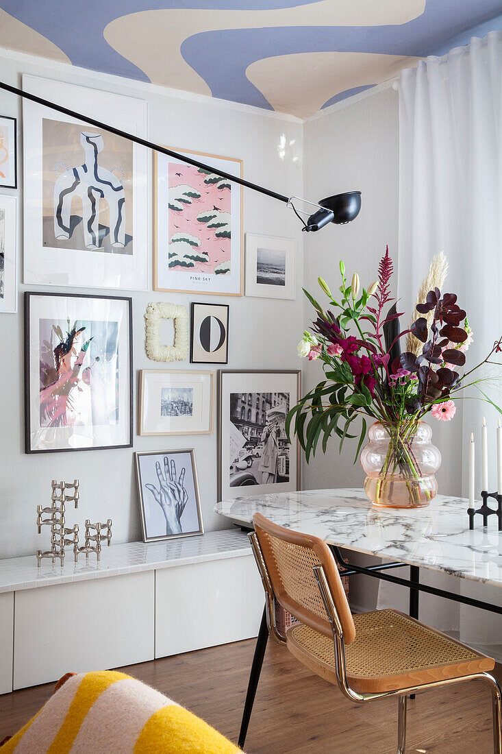 Dining area with marble table top, colorful artwork and bouquet of flowers