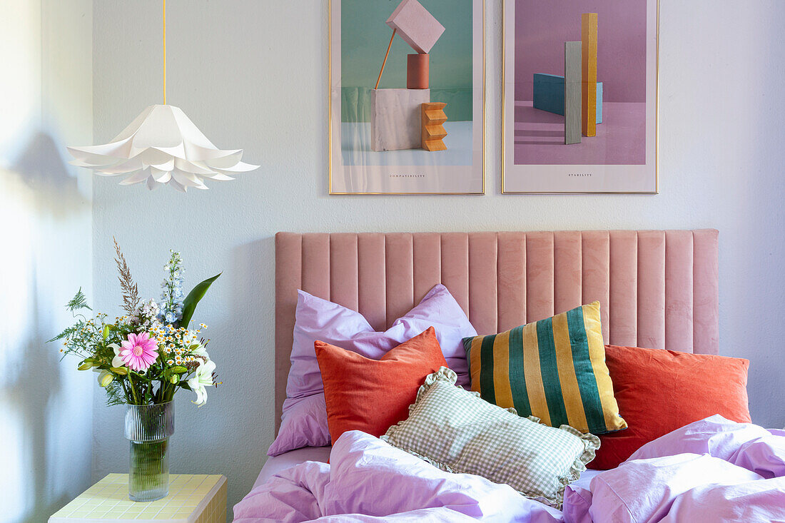 Bed with upholstered headboard, colorful throw pillows and modern wall art in the bedroom