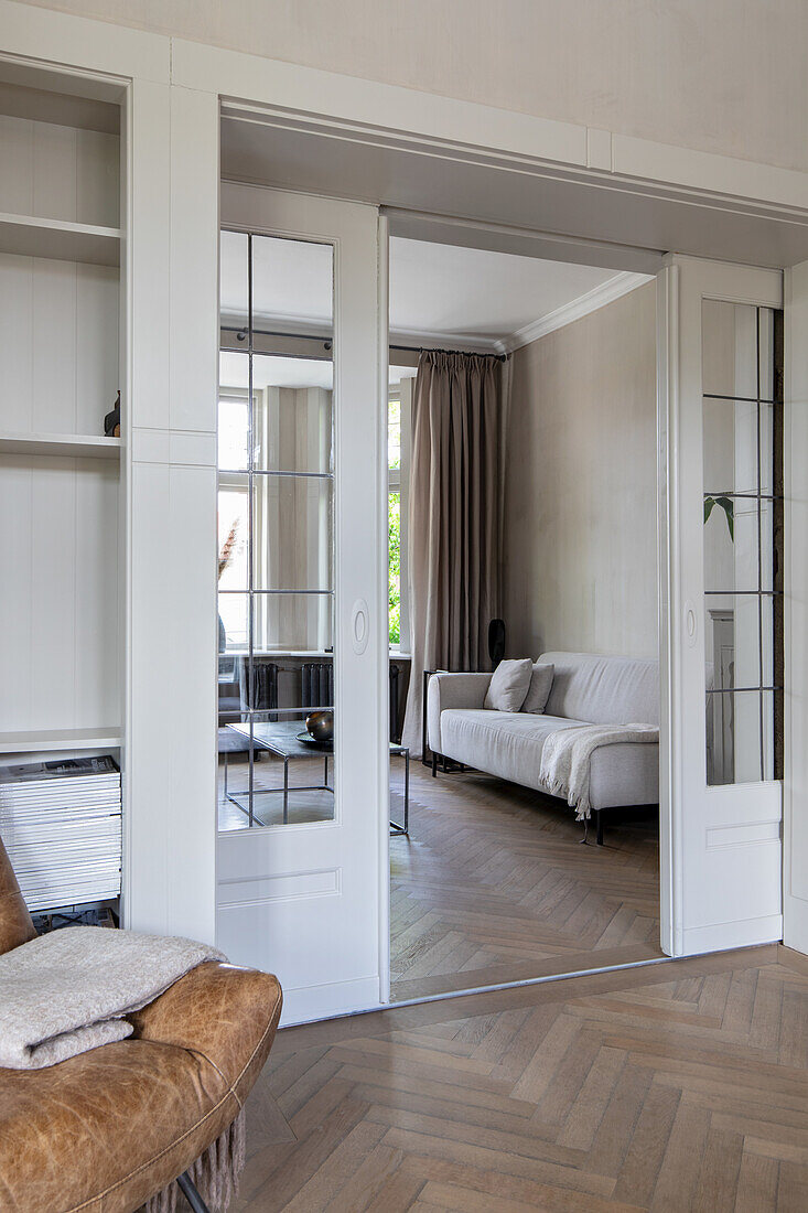 View into a bright living room with parquet flooring and glazed sliding doors