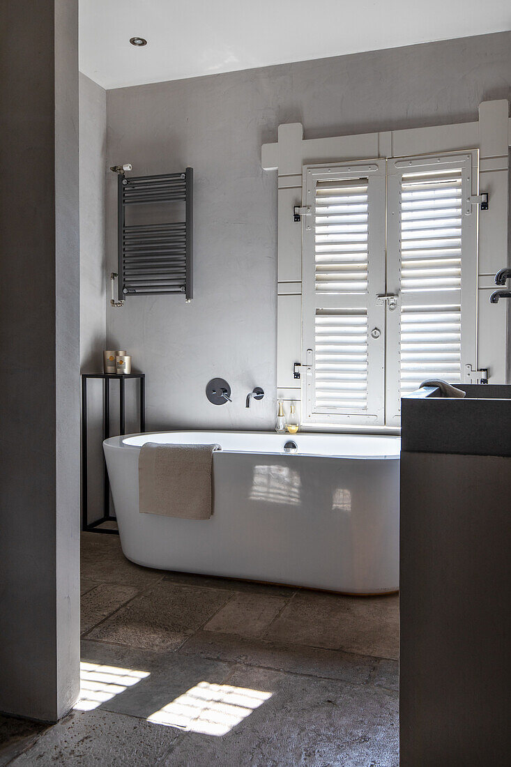 Bathroom with free-standing bathtub and white shutters