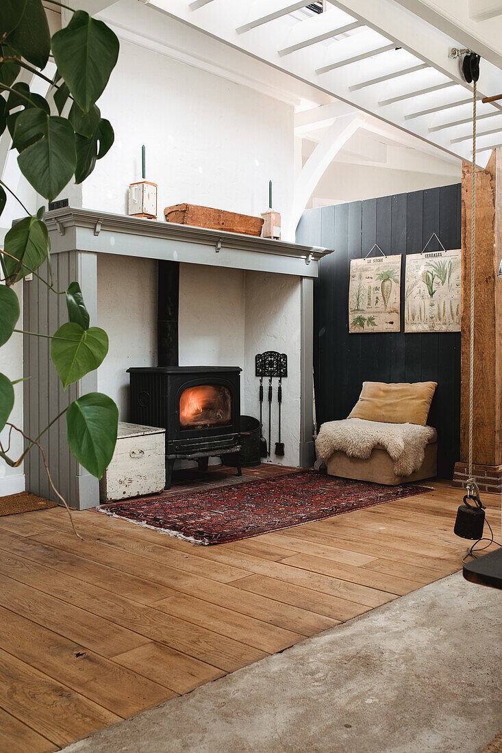 Wood-burning stove with wood-panelled wall and oriental rug in a living room