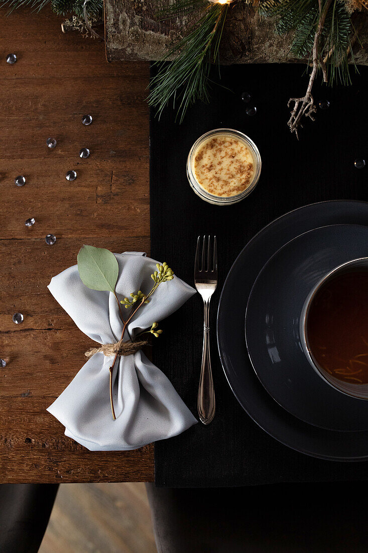 Dark wooden table with winter table decorations and black crockery