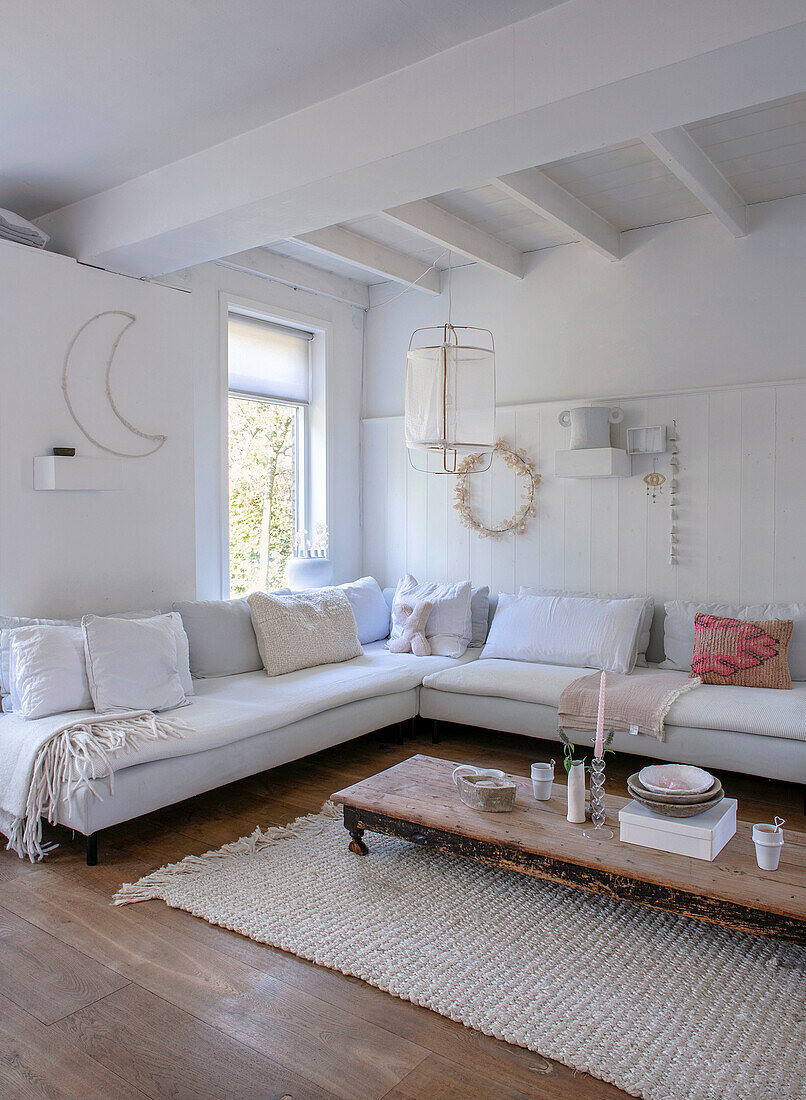 Corner sofa in the living room with wooden table and light-colored decoration