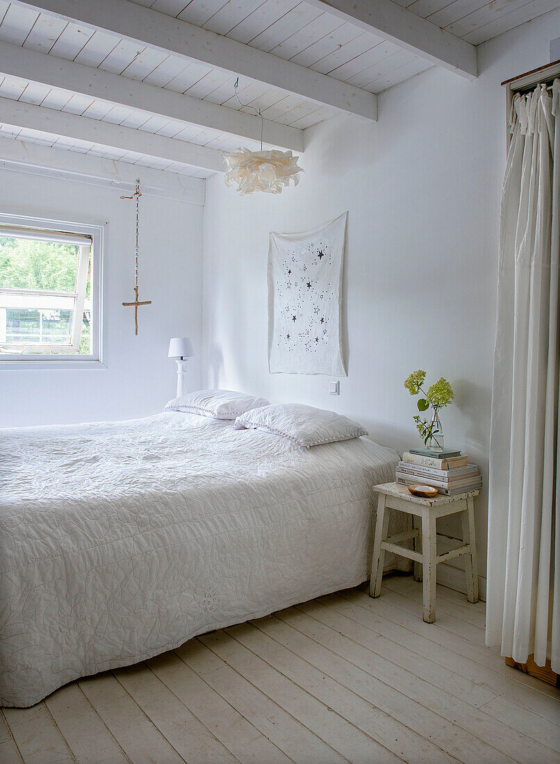 Bedroom in white with wooden beamed ceiling and wooden side table