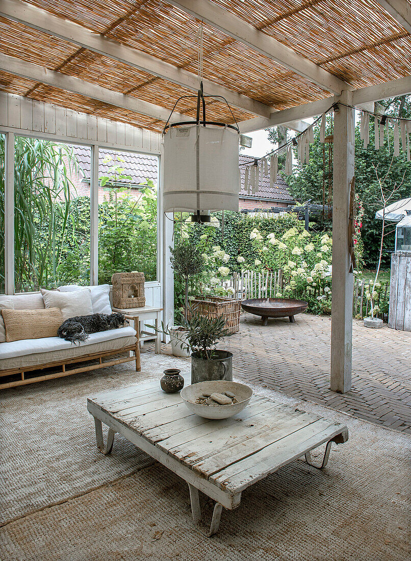 Überdachte Terrasse mit Holztisch und Outdoor-Sofa