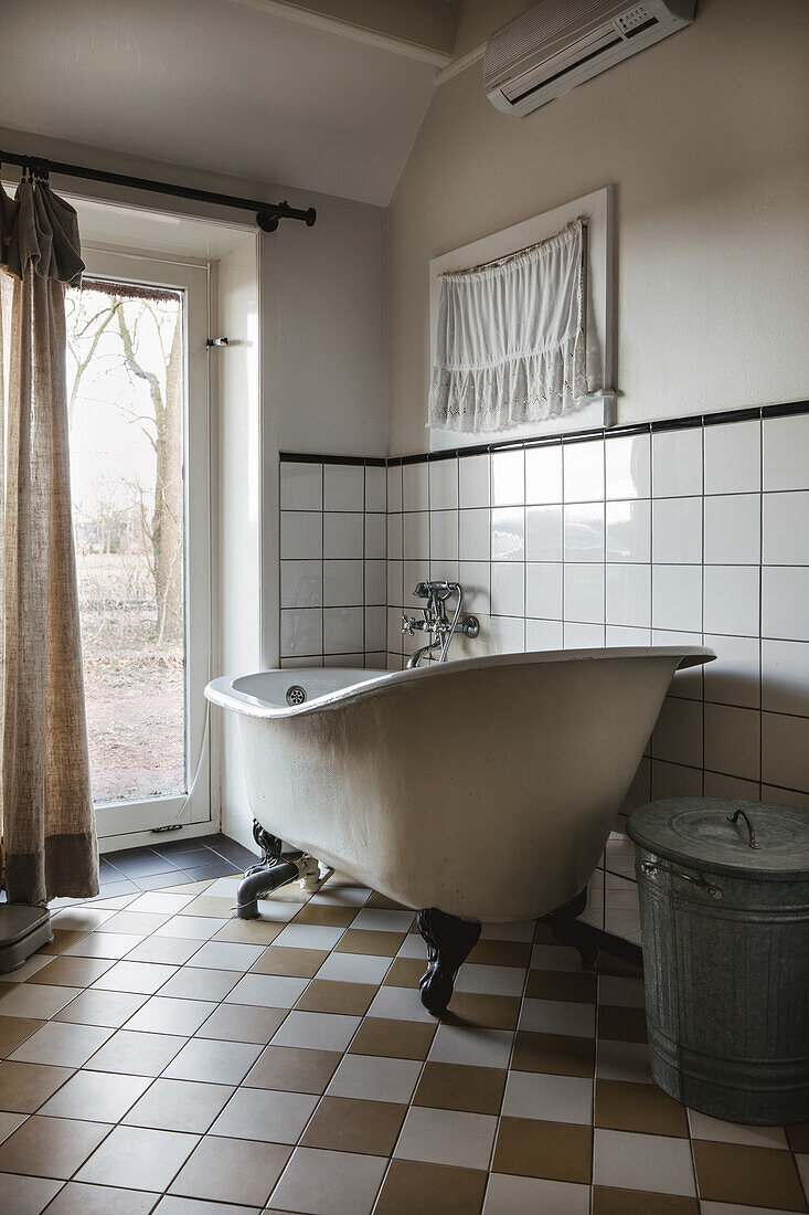 Vintage-style freestanding bathtub with chequered tiles