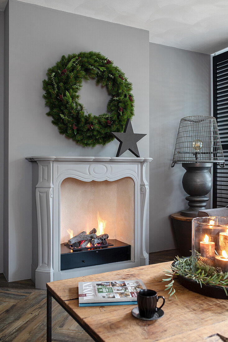 Fireplace decorated for Christmas with a green wreath and candle arrangement