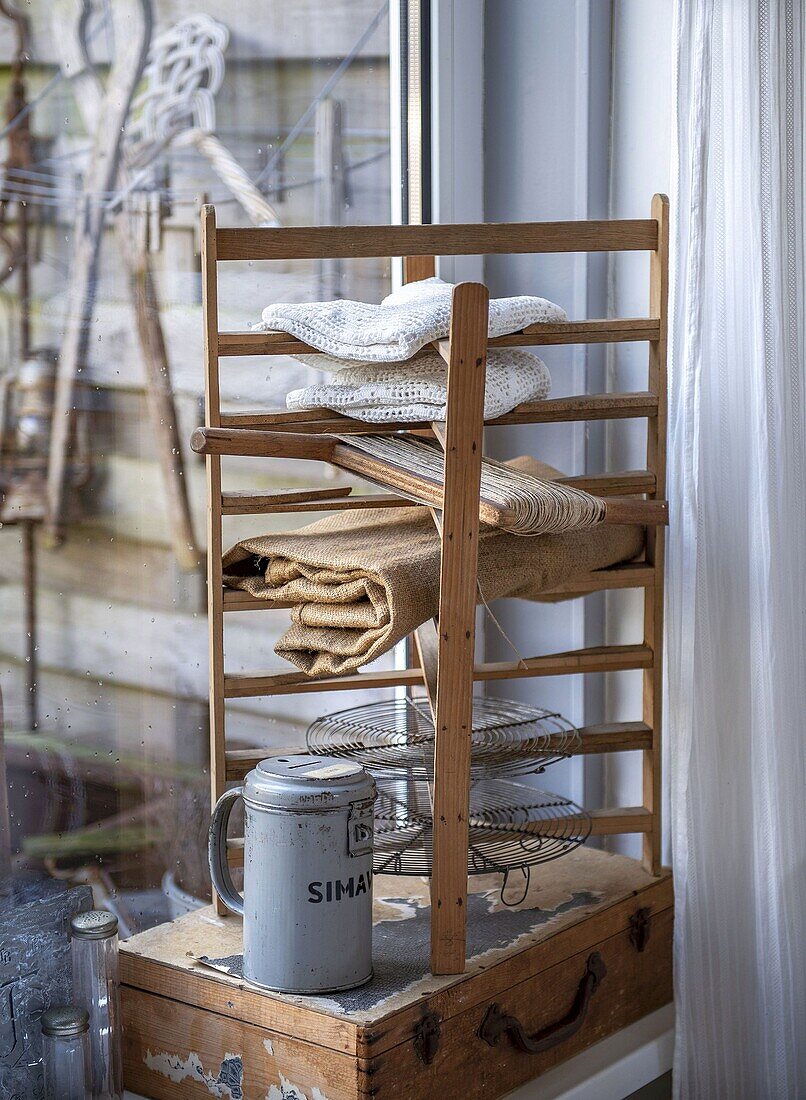 Wooden shelf with folded linen cloths and metal jug