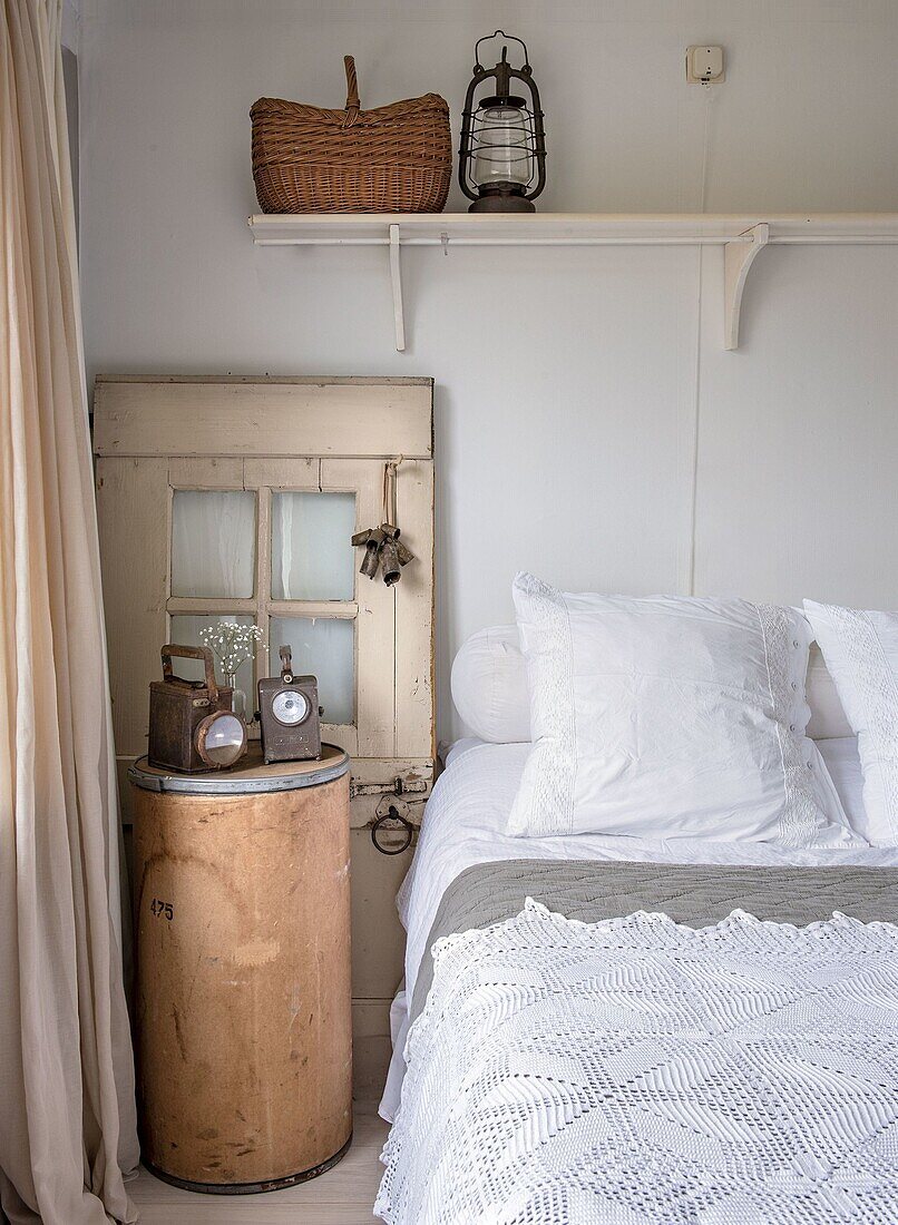 Bedroom with white textiles, lantern and round bedside table