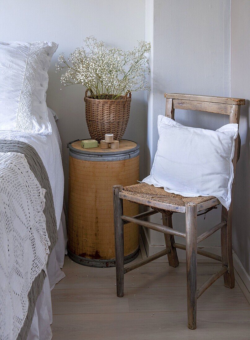 Vintage wooden chair and bedside table with flower arrangement in the bedroom