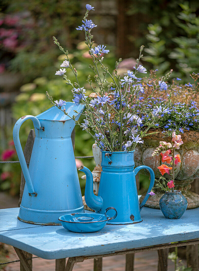 Blue vintage jugs with blooming wildflowers on garden table