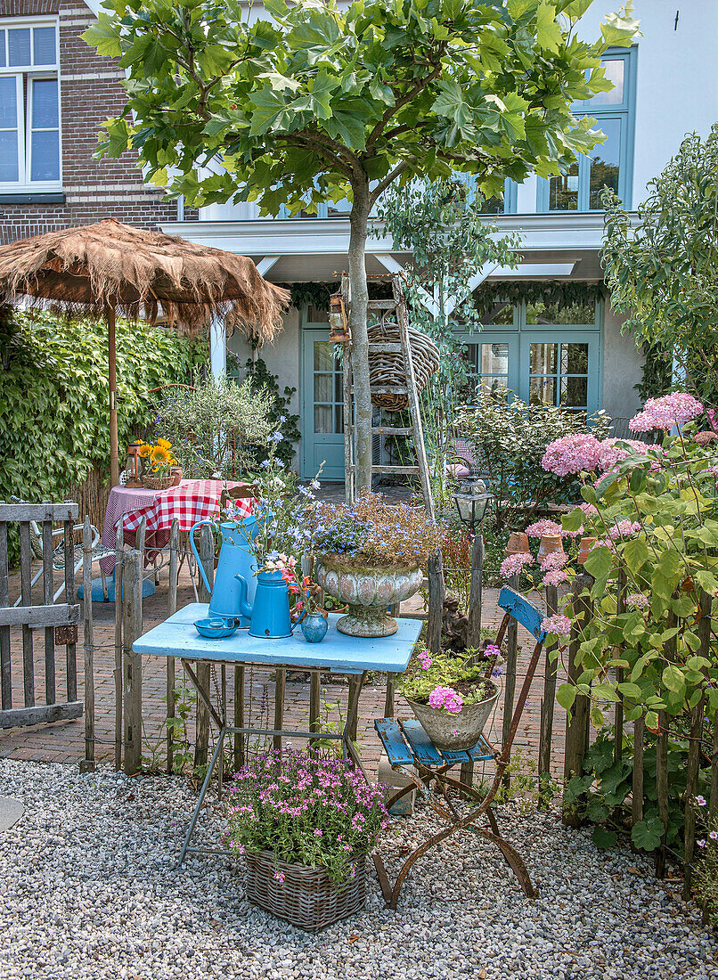 Seating area in the garden with blue table, chair and flower arrangement