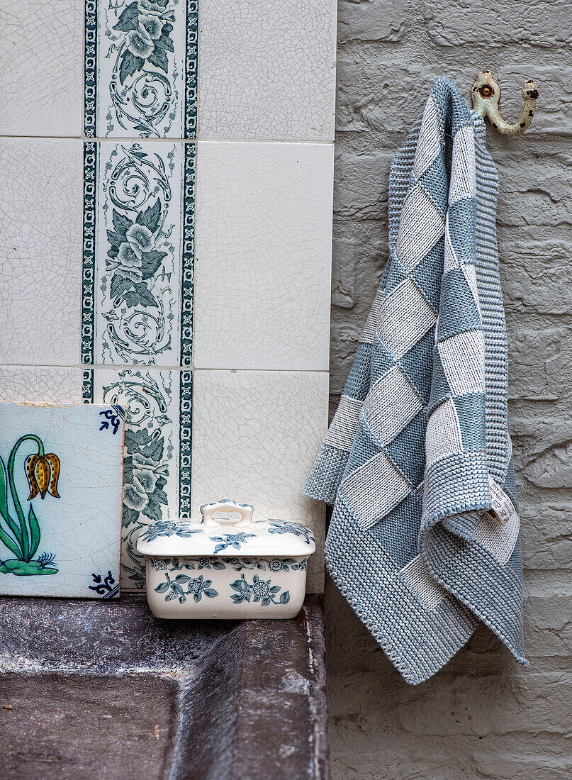 Tiled wall with blue and white accents, porcelain box and patterned towel