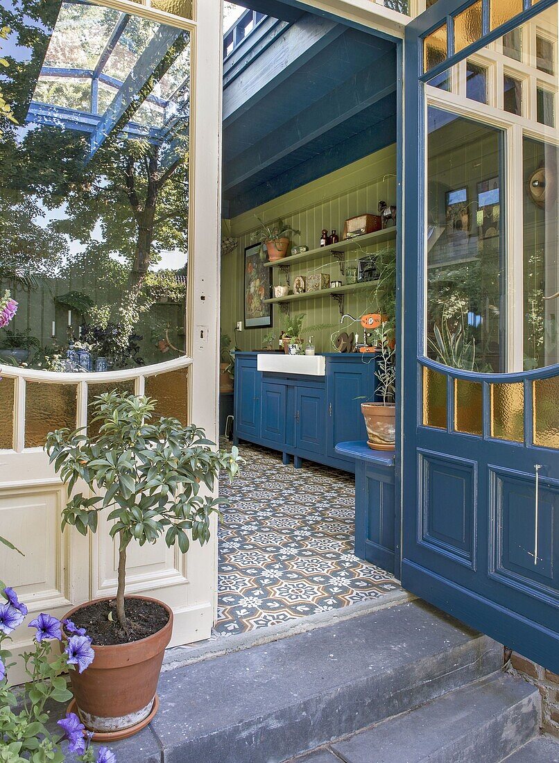 View of conservatory with patterned floor tiles and blue kitchen with green wall