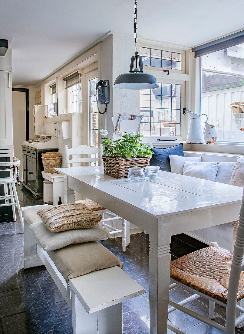 Bright dining area with white wooden table and window seat bench