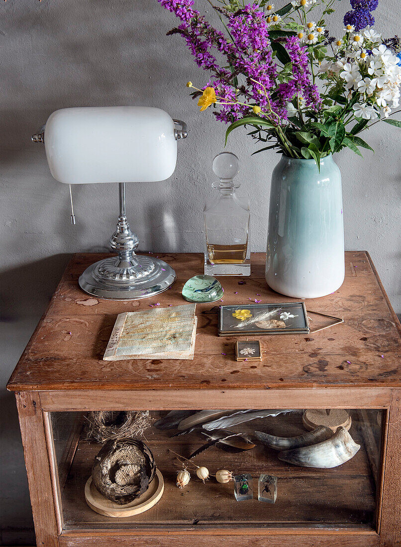 Vintage-Schrank mit Blumenstrauß, Lampe und Dekorationen