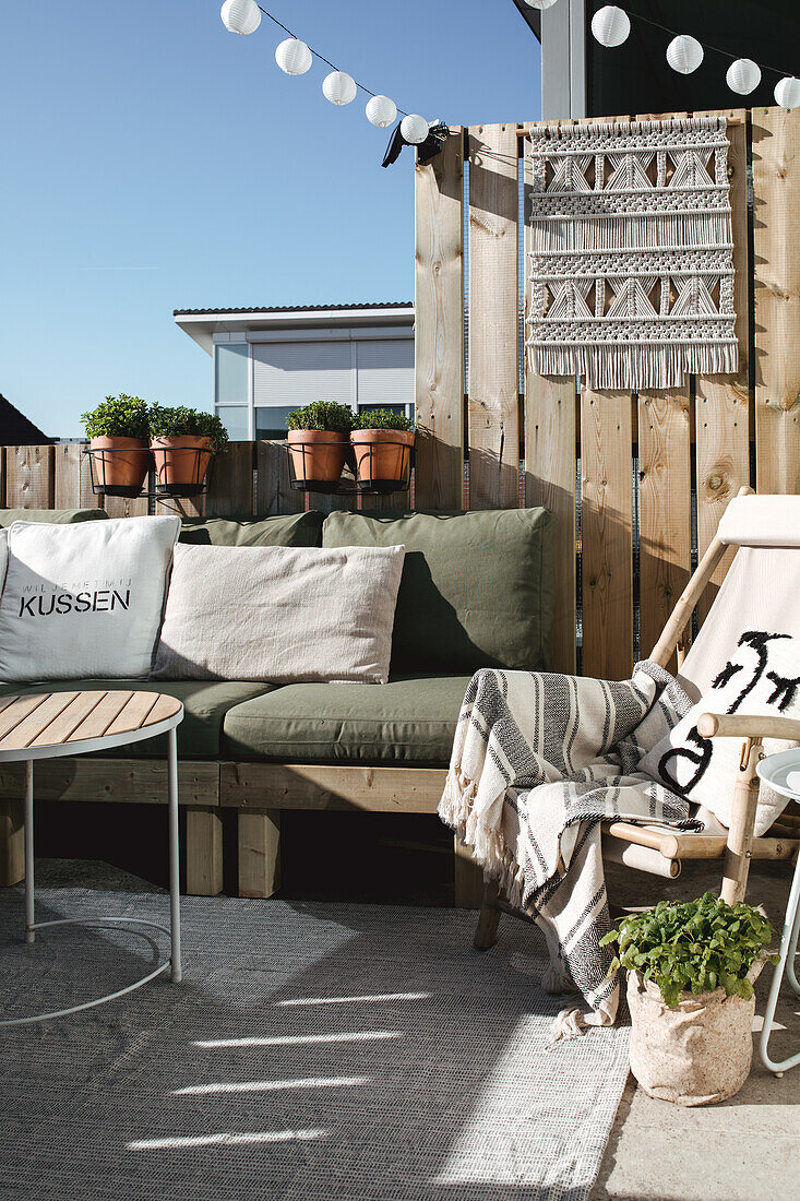 Cosy patio corner with pallet sofa and macramé wall hanging