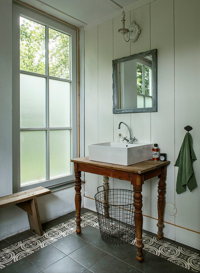 Bathroom with antique washbasin and patterned tiled floor