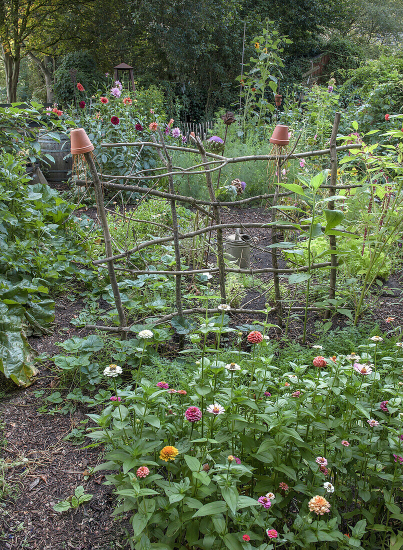 Blühender Garten und Rankhilfe aus Ästen im Sommer