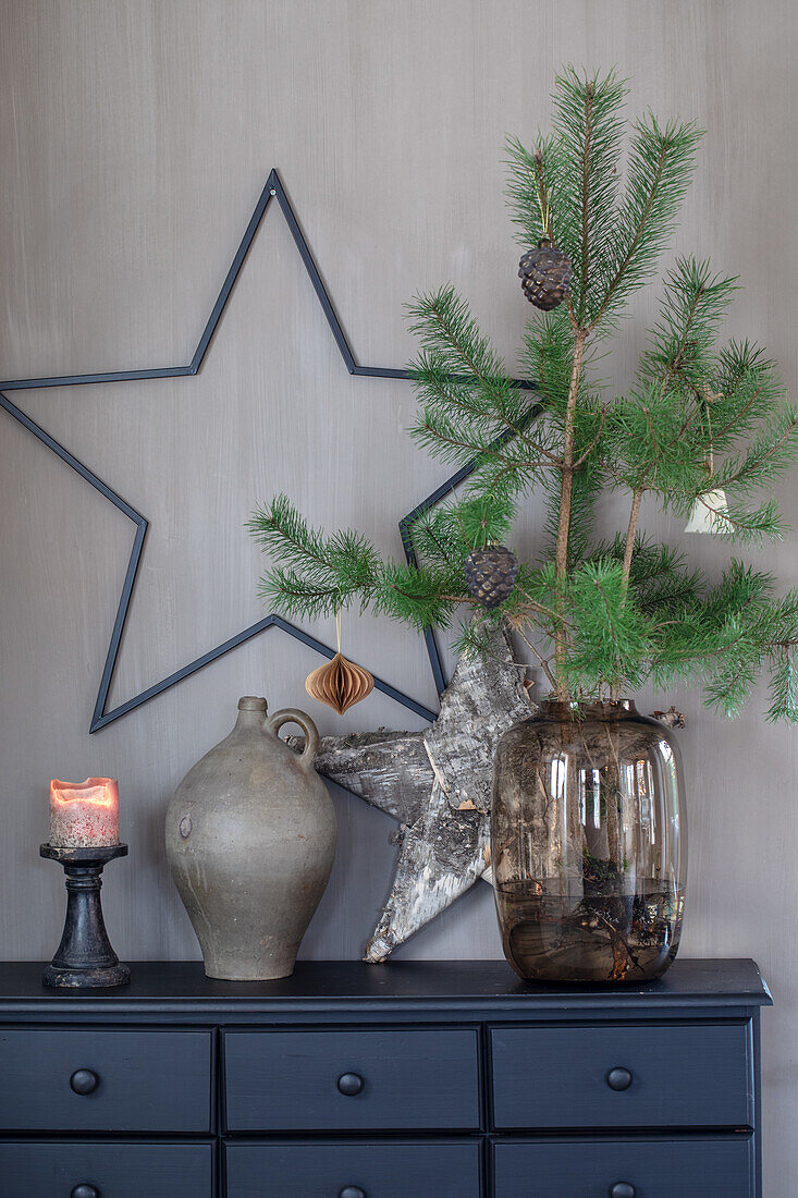 Chest of drawers decorated for Christmas with vases, stars, pine branches and candles