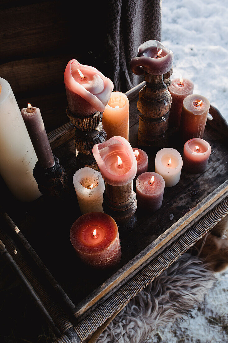 Rustic tray with burning pillar candles in the snow