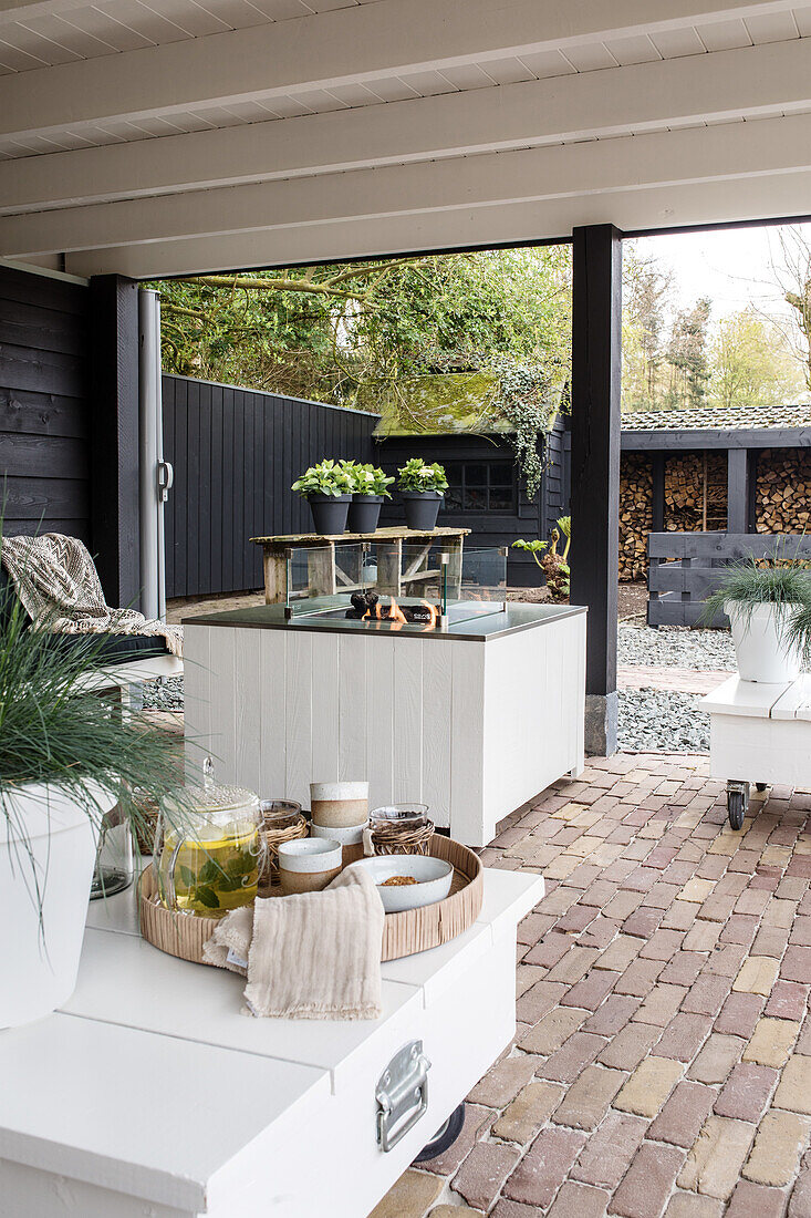 Covered terrace with white furniture and fire pit