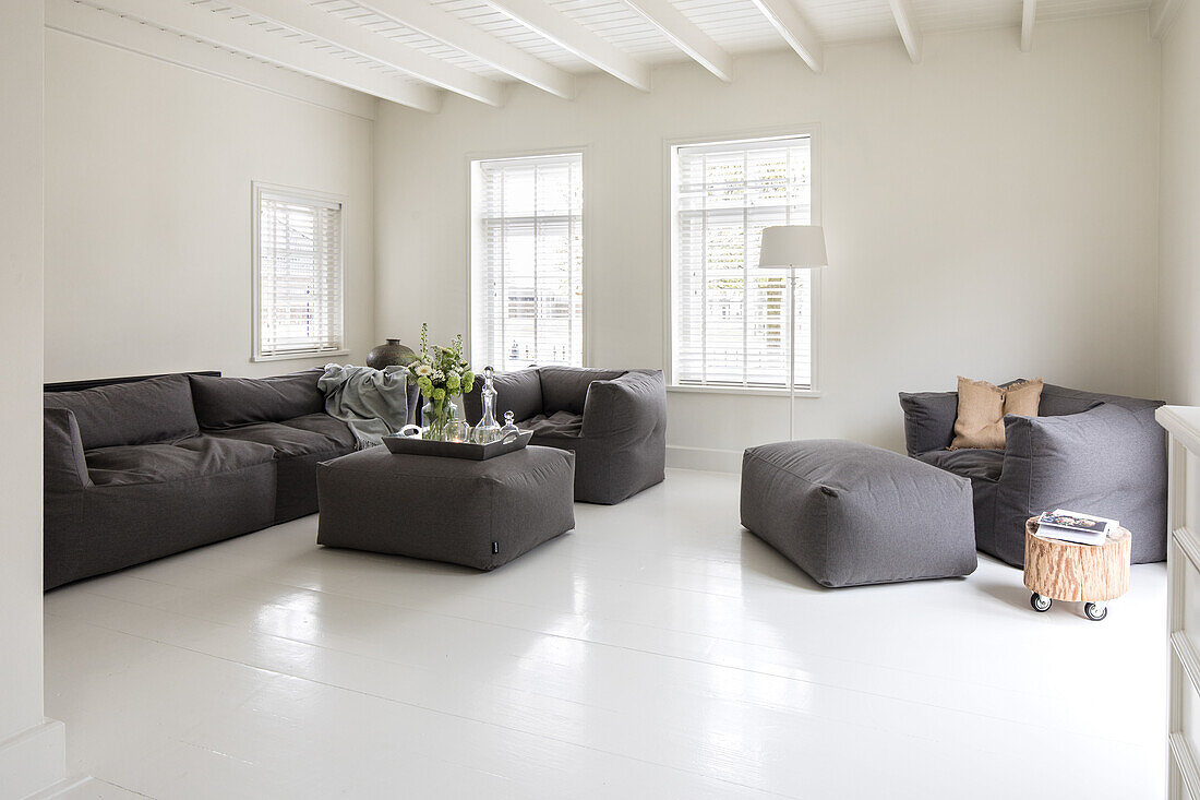 Open-plan living room with grey upholstered furniture and white walls