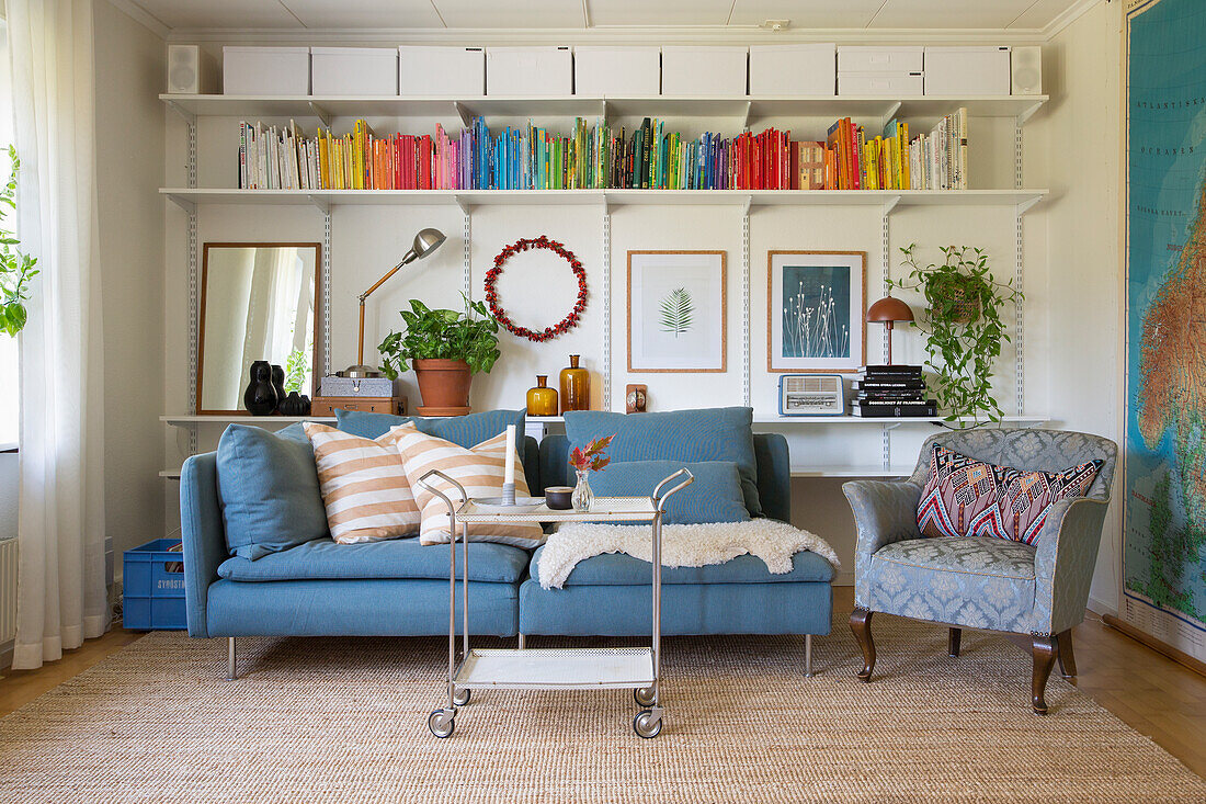 Wohnzimmer mit blauem Sofa, Bücherregal und Sessel im Vintage-Stil