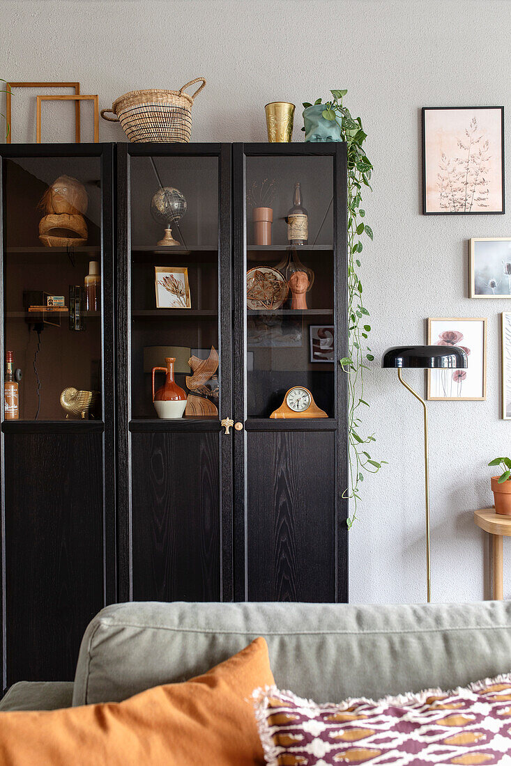 Black display cabinet with wall pictures and floor lamp in the living room