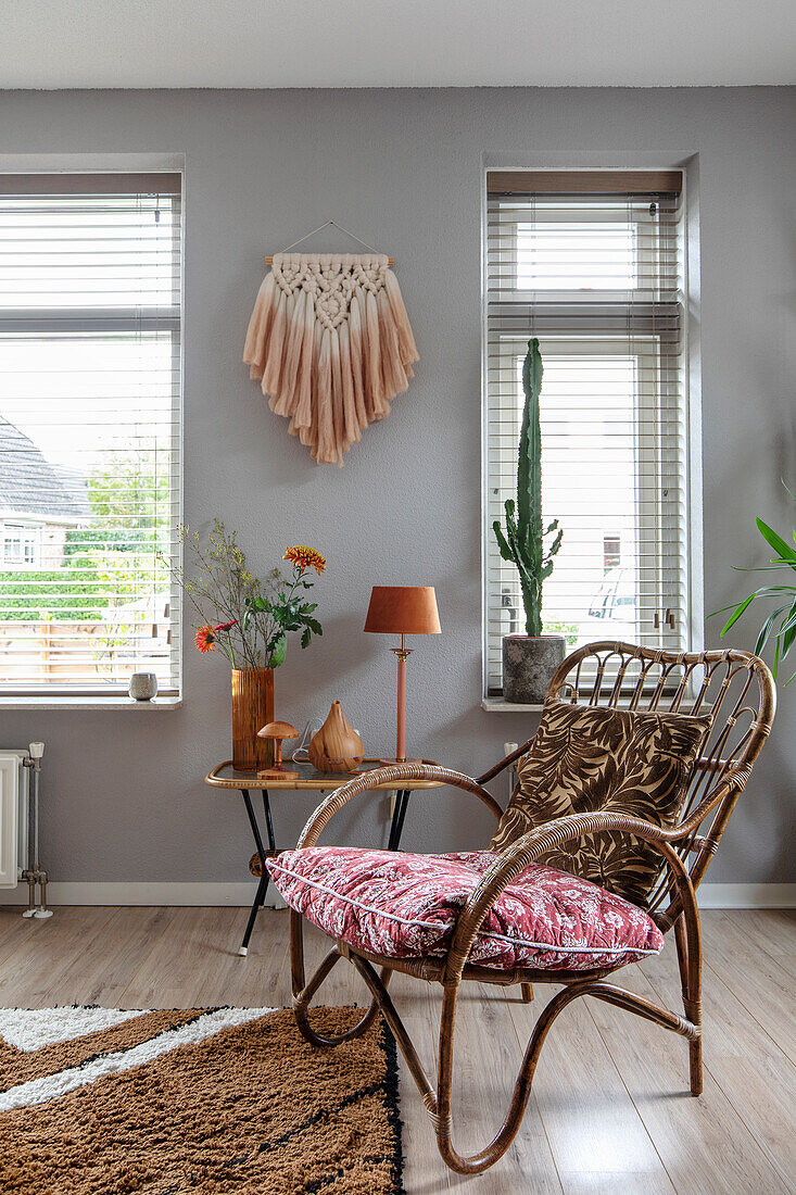 Rattan armchair with patterned cushions and macramé wall hanging