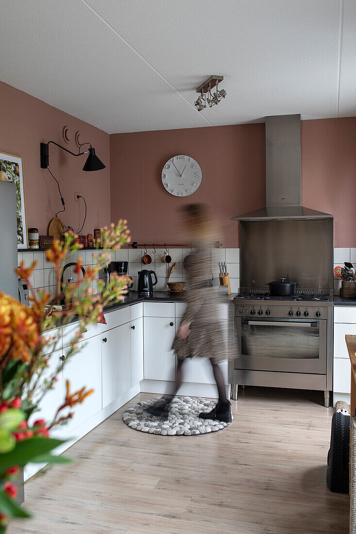 White kitchen with gas hob and pink wall paint