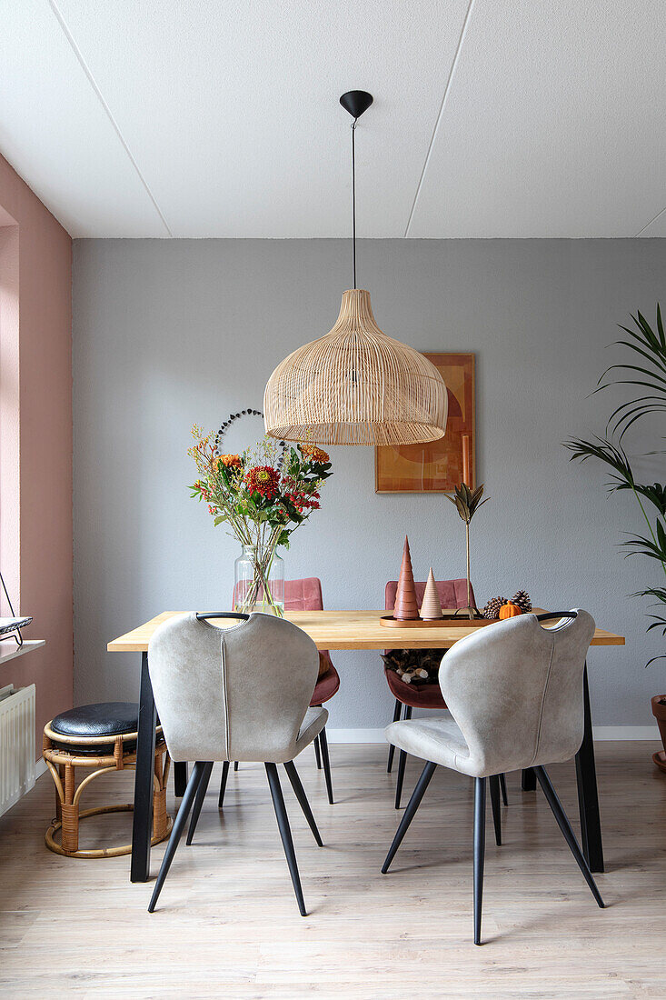 Bright dining area with wooden table, rattan pendant light and grey chairs