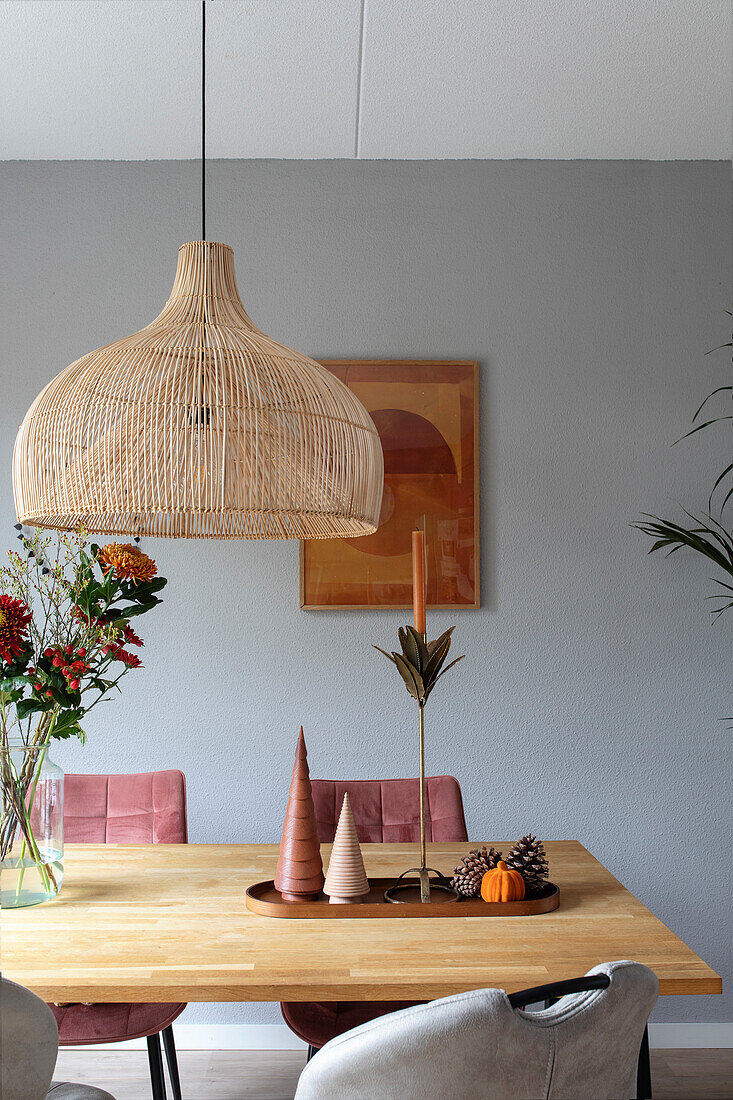 Rattan pendant light above a dining table with autumnal decoration