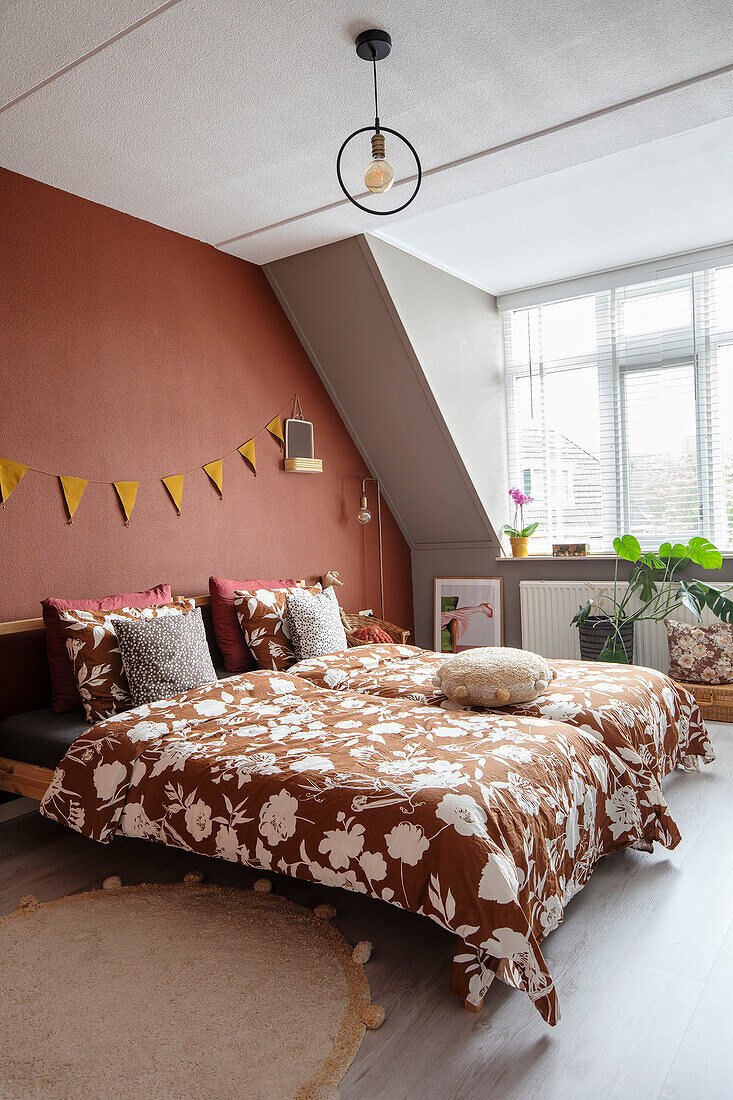 Sloping ceiling bedroom with patterned textiles in terracotta colours