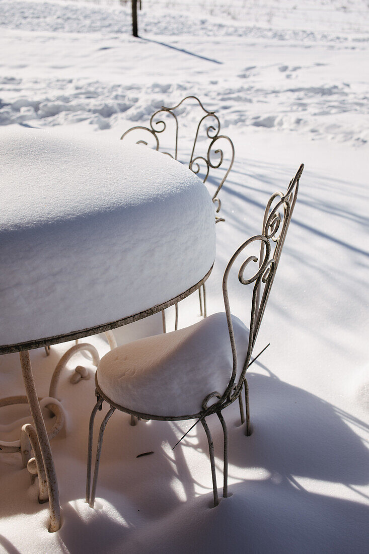 Verschneiter Tisch und Stühle im Wintergarten