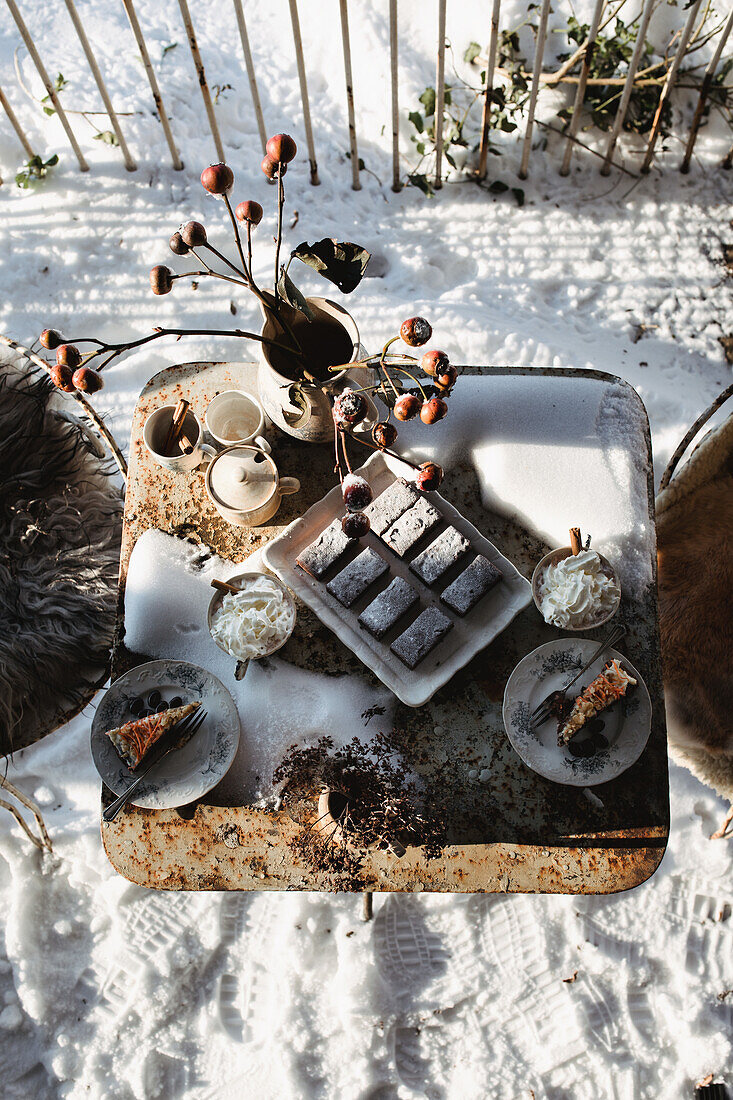 Winter coffee party in the garden on a snow-covered table