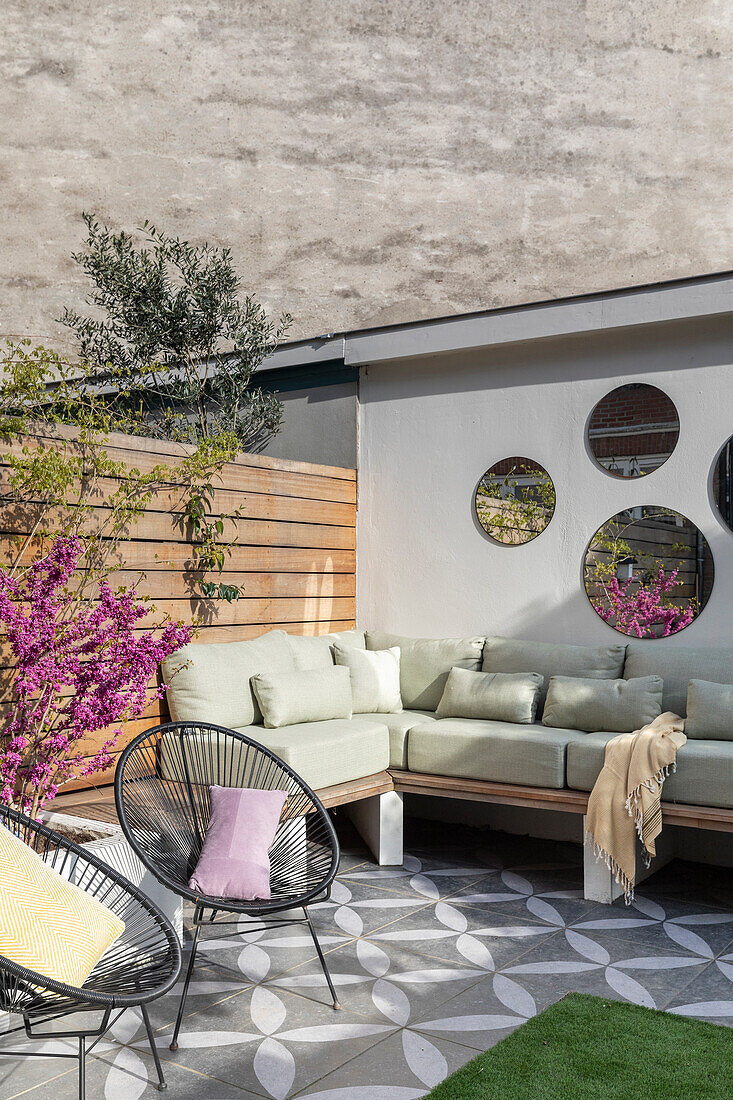 Modern terrace with corner sofa, round mirrors and patterned tiles