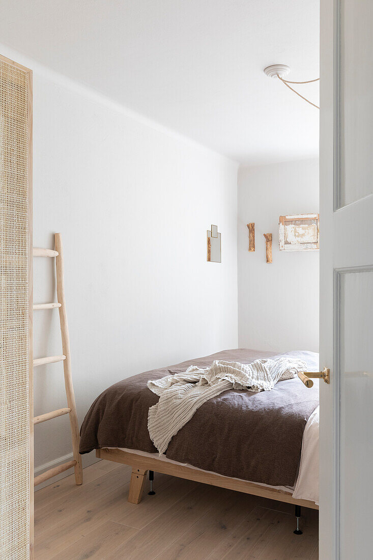 Simple bedroom with wooden bed and decorative ladder