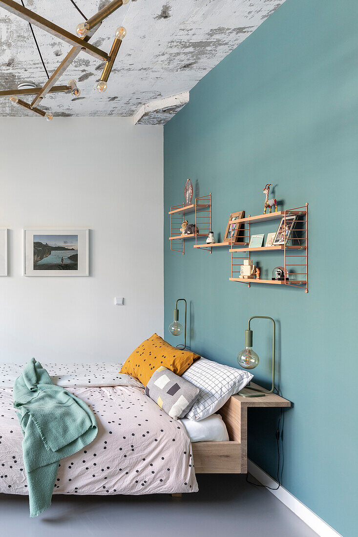 Bed in modern bedroom with blue-green accent wall