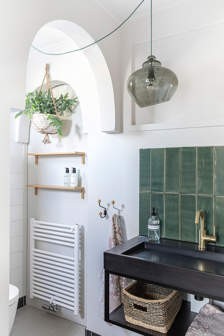 Modern bathroom with black washbasin, gold tap and green tiles