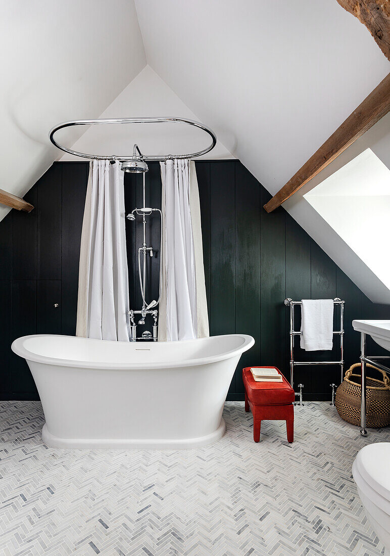 Freestanding bathtub, dark accent wall and sloping ceiling in the bathroom