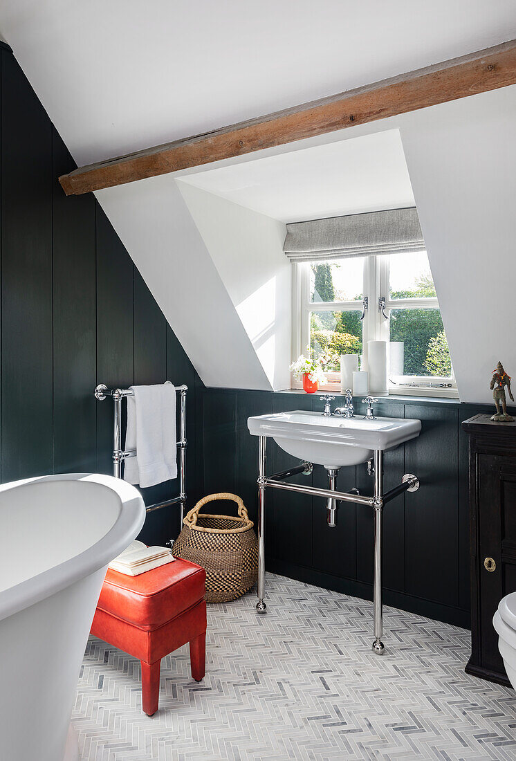 Bathroom with free-standing bathtub, sloping roof and herringbone mosaic tiles